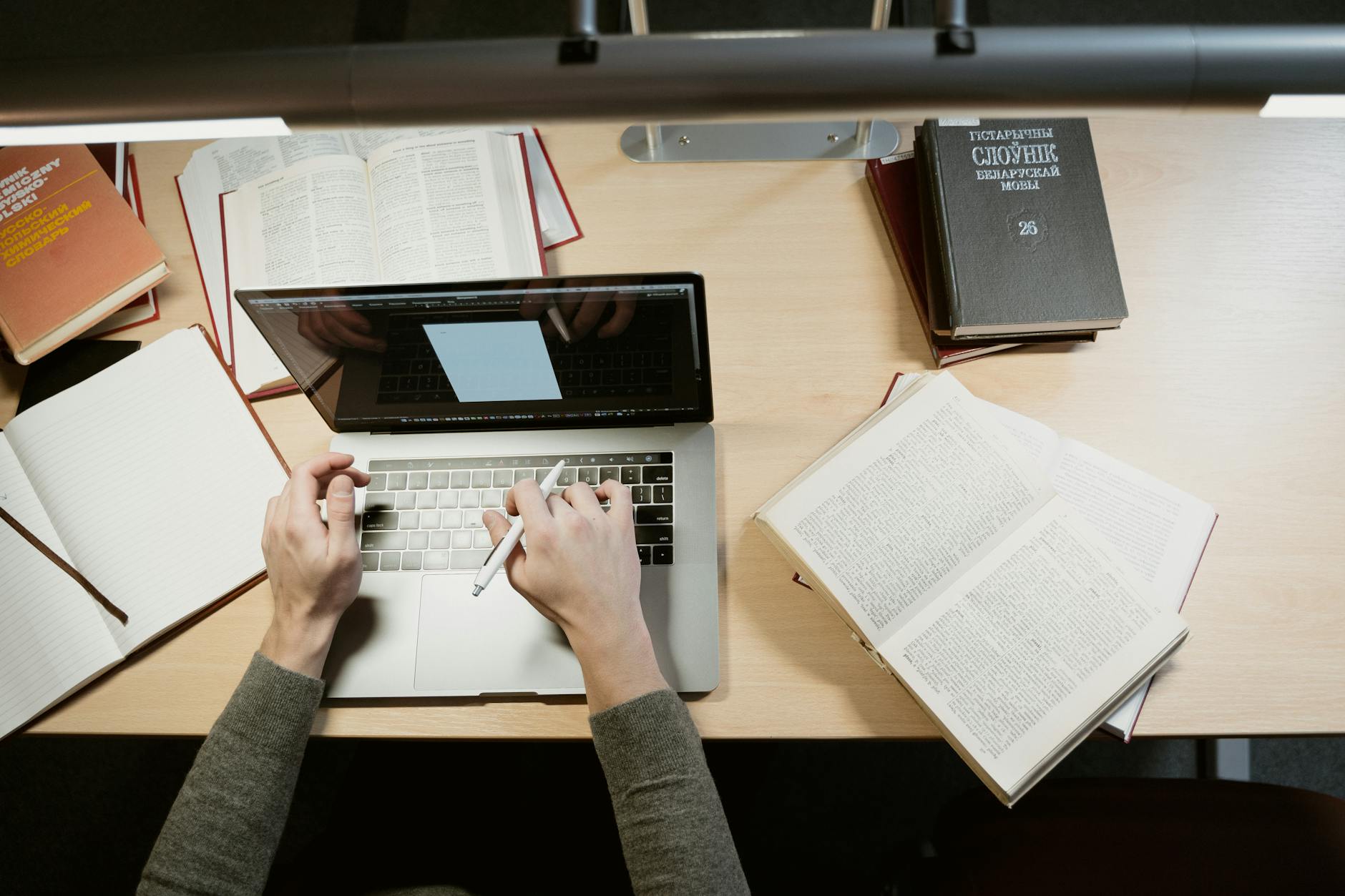 A student researching online for debate preparation, showing a laptop and books.