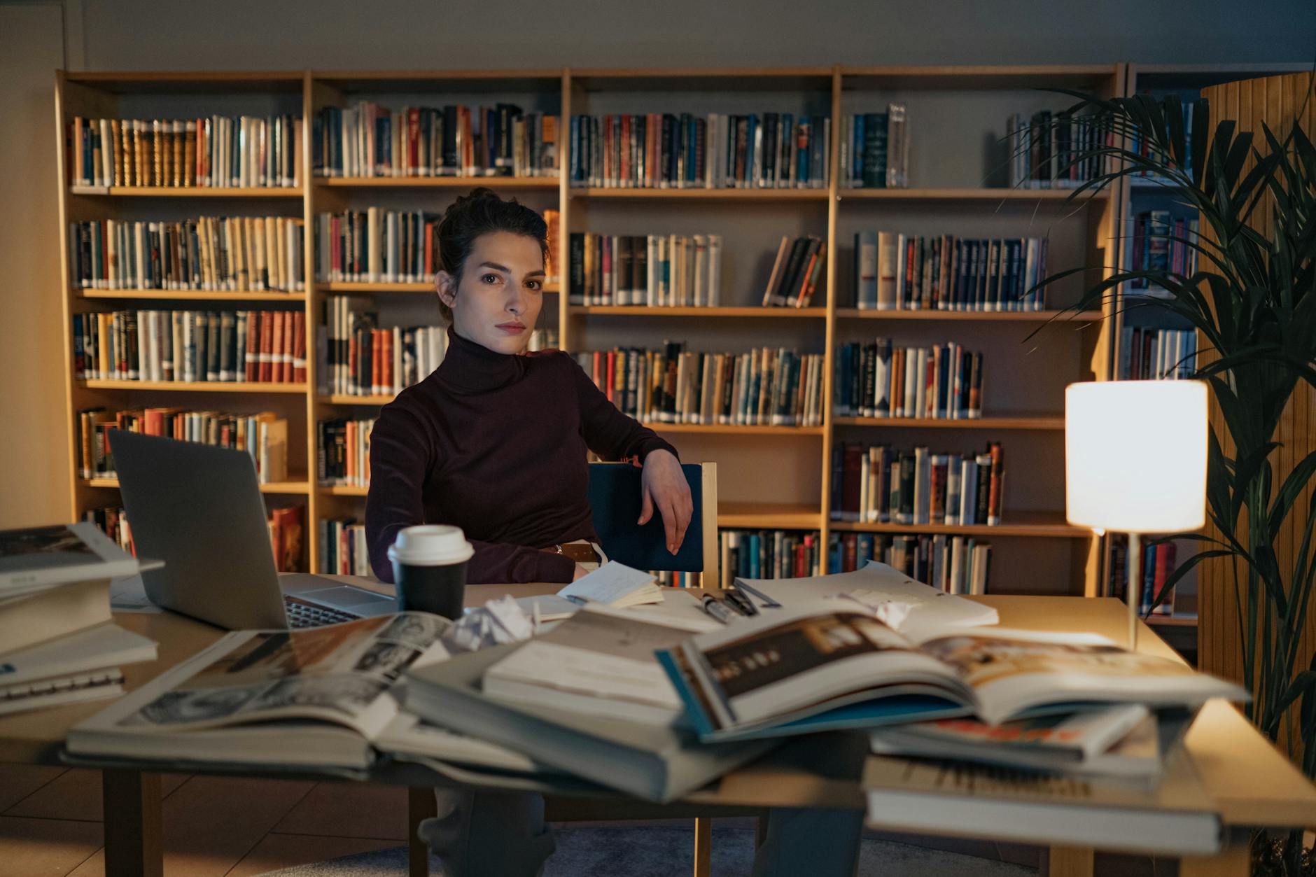 A person researching at a desk with books and a laptop open. — debate competition preparation