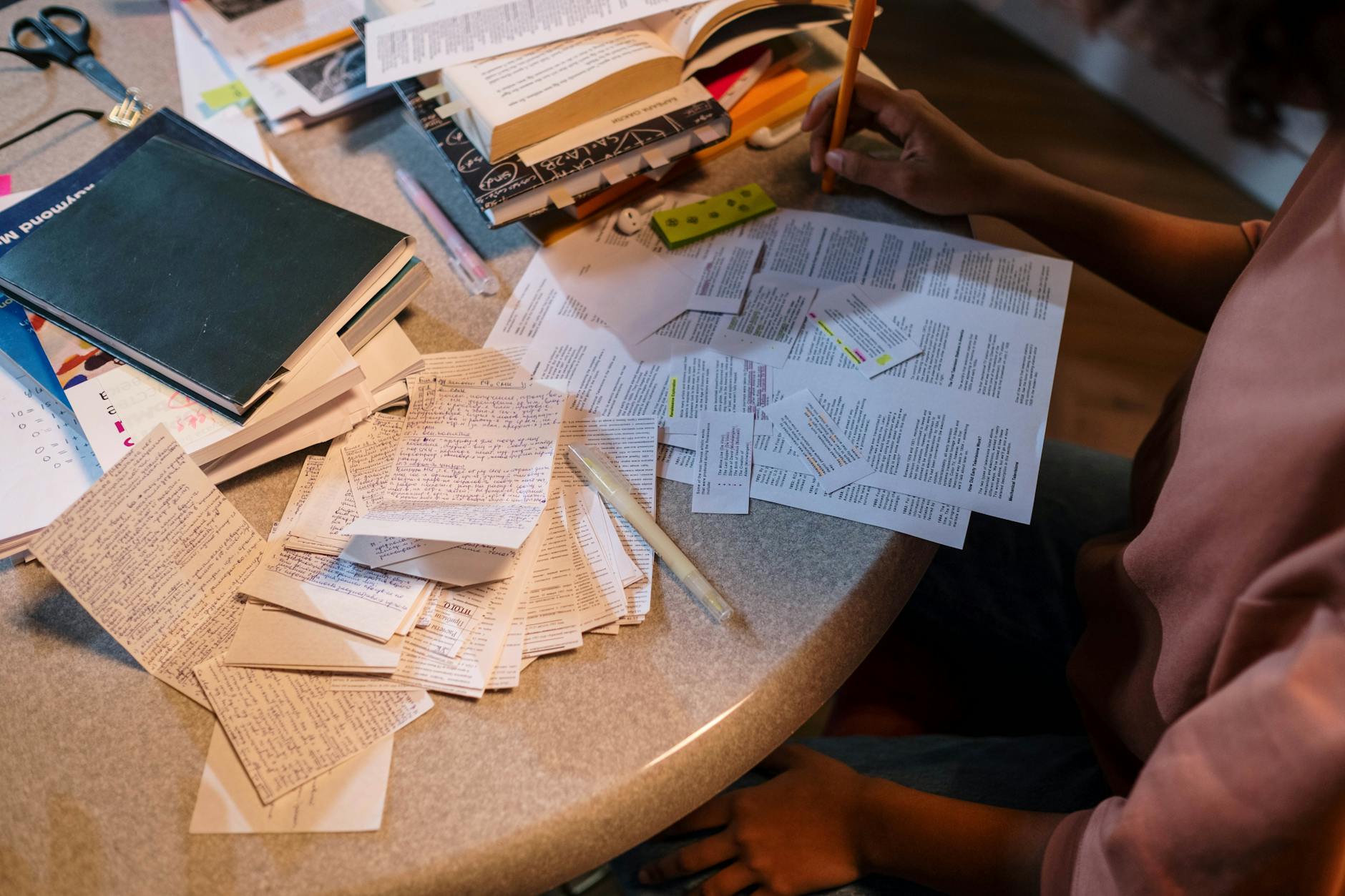A student studying with books and notes spread out, illustrating effective research techniques for debate preparation tips.