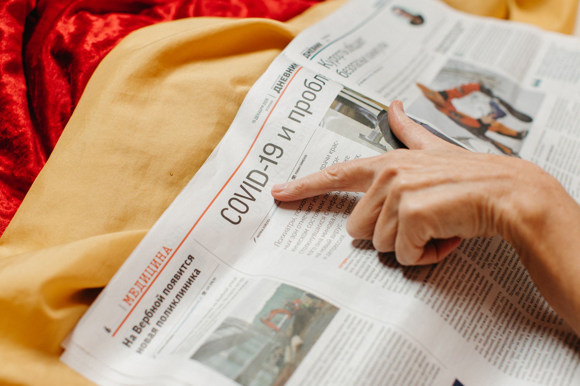 A close-up of a person reading a newspaper with current headlines. — current events debates