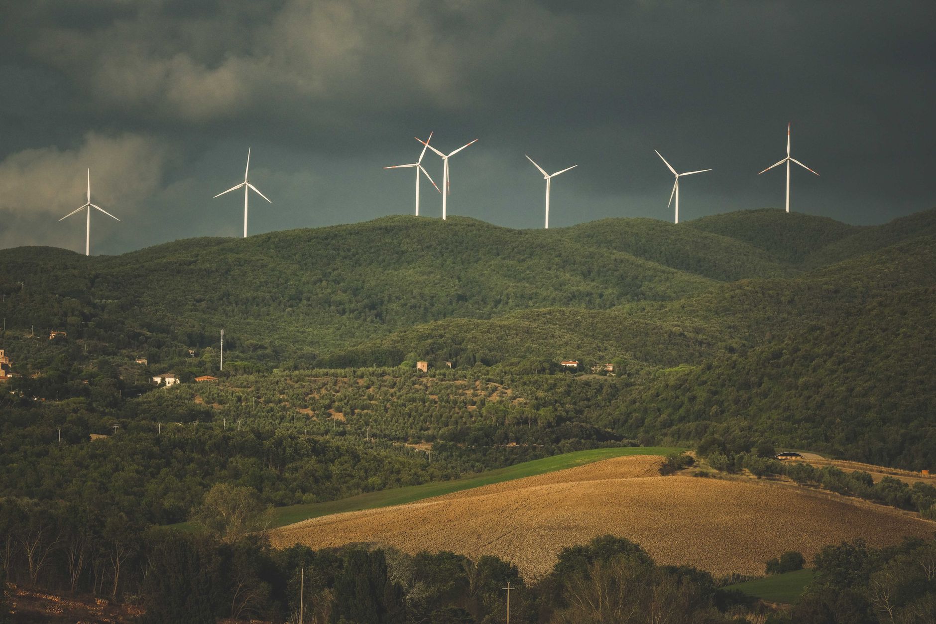 A wind turbine farm on rolling hills, showcasing the role of wind energy in the discussion on renewable resources. — ren…