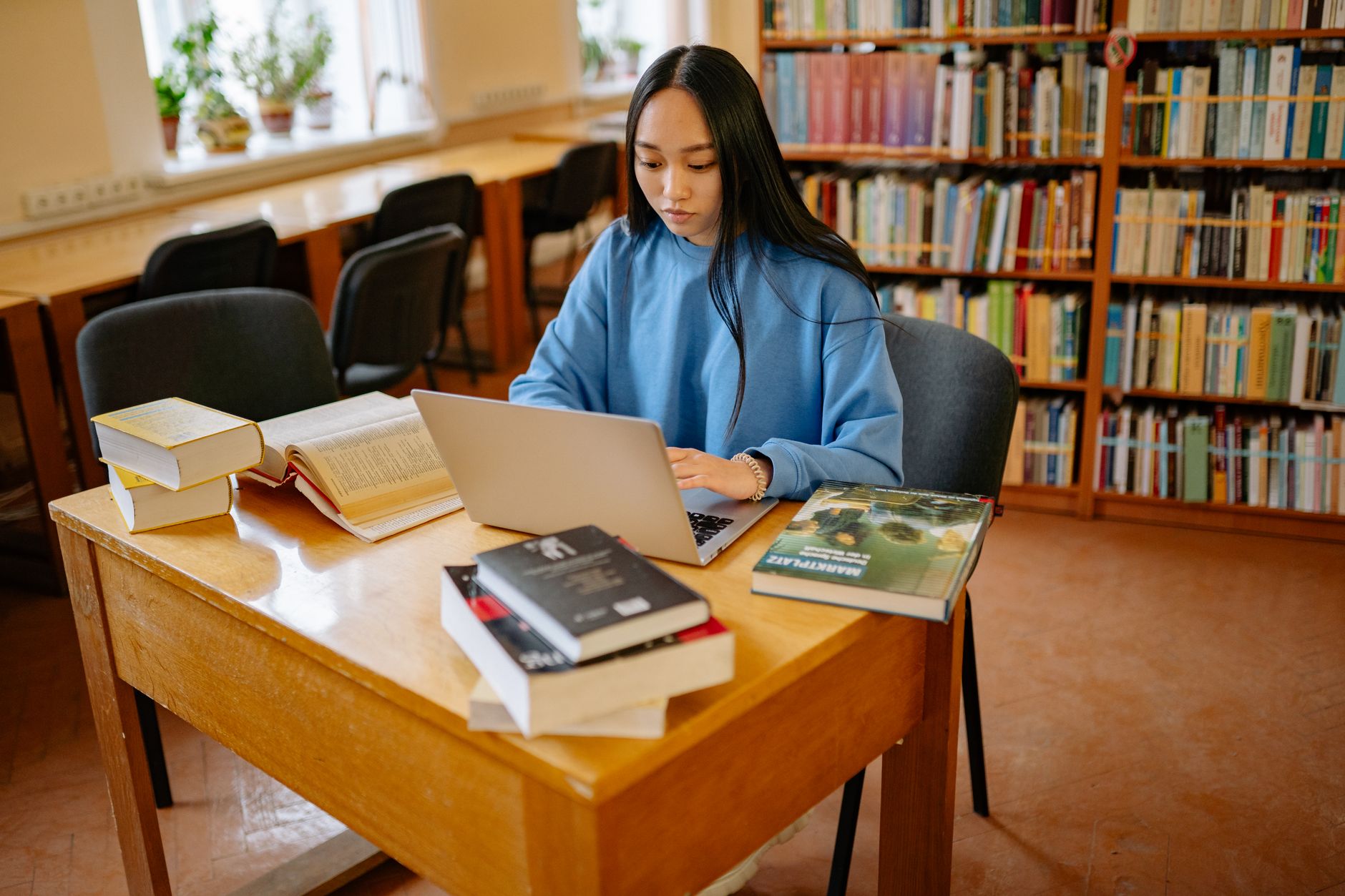 An image of a person researching debate topics with books and a laptop, illustrating preparation for a live debate. — li…