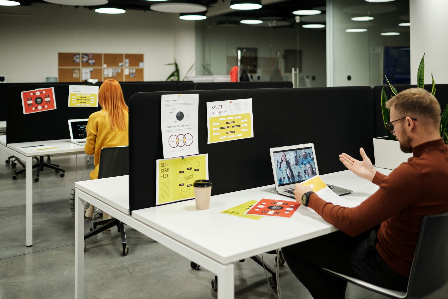 An office space showing employees collaborating at their desks. — remote work debate
