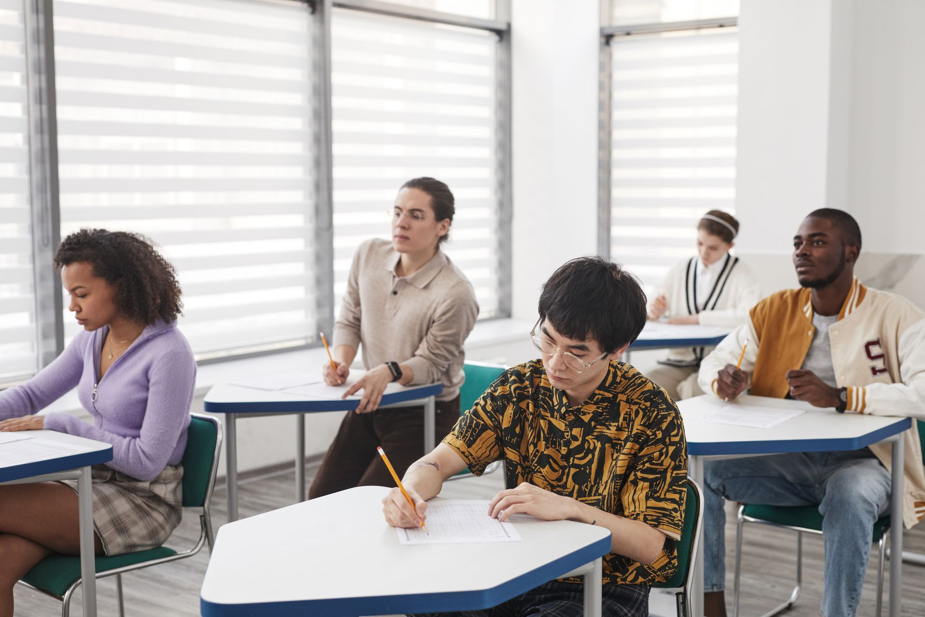 A classroom setting showing students engaging in various assessment activities related to the exam system debate.