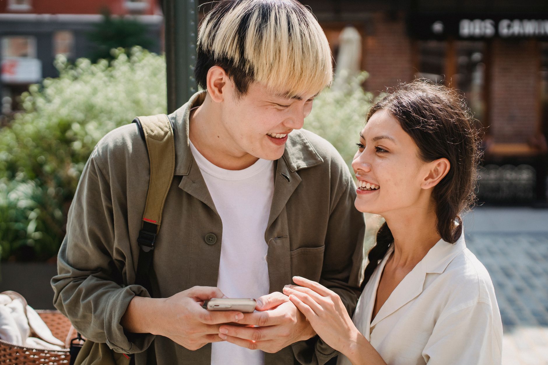A couple engaging with each other while using their smartphones, highlighting the blend of online and offline interactions…
