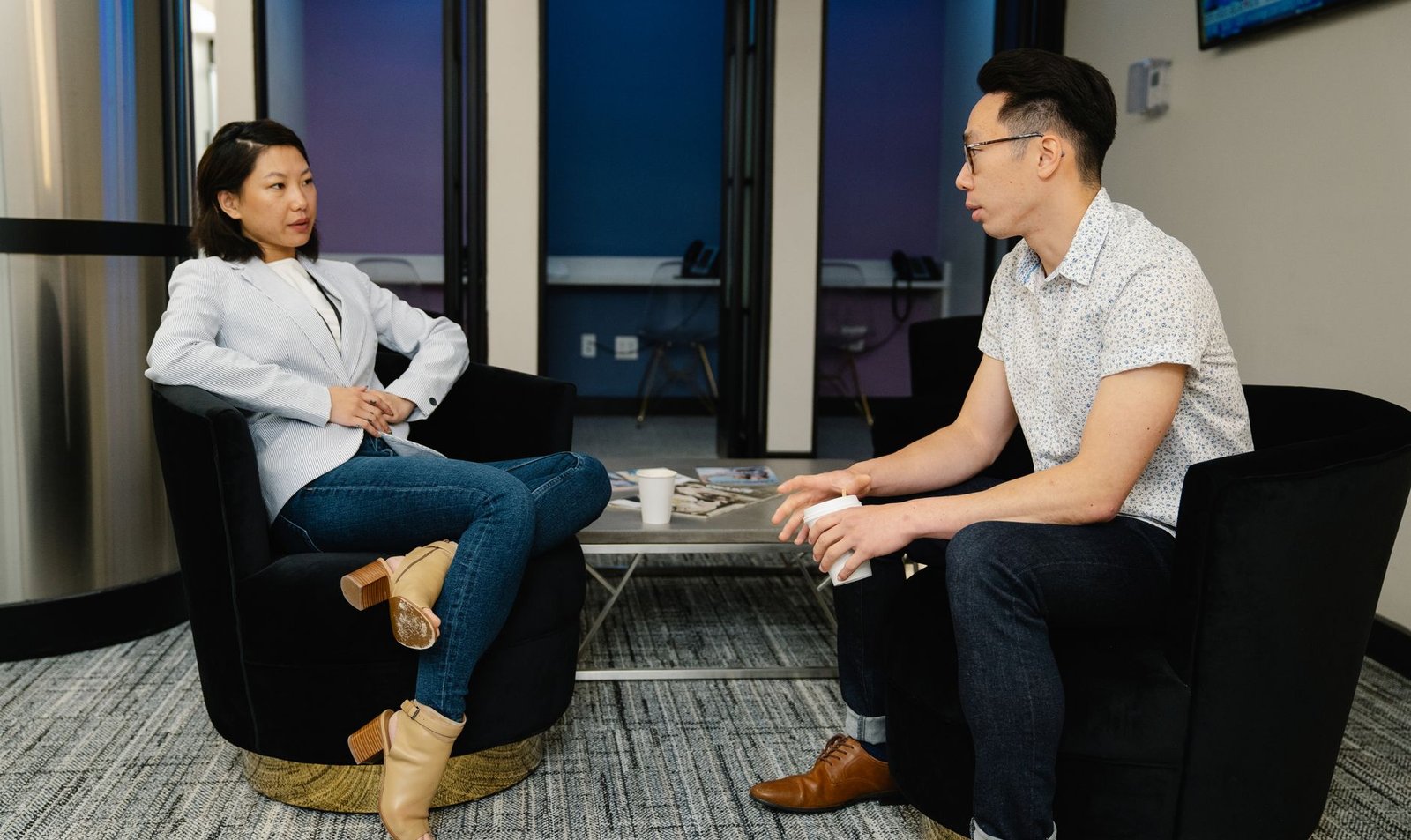 A professional setting where two individuals are engaged in a negotiation, showcasing body language and active listening. …