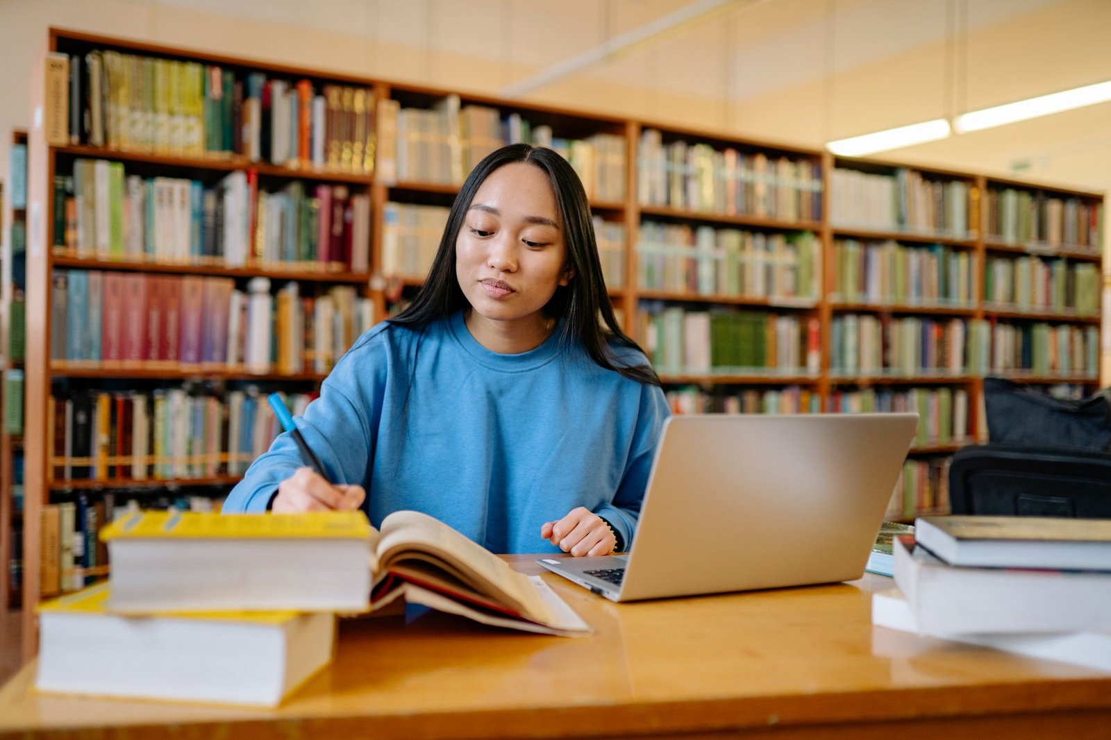 A student researching debate topics at a library with books and notes around. — debate preparation