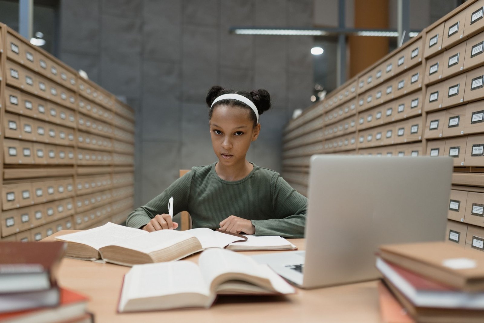 Image showing a student researching debate topics with books and a laptop. — debate research