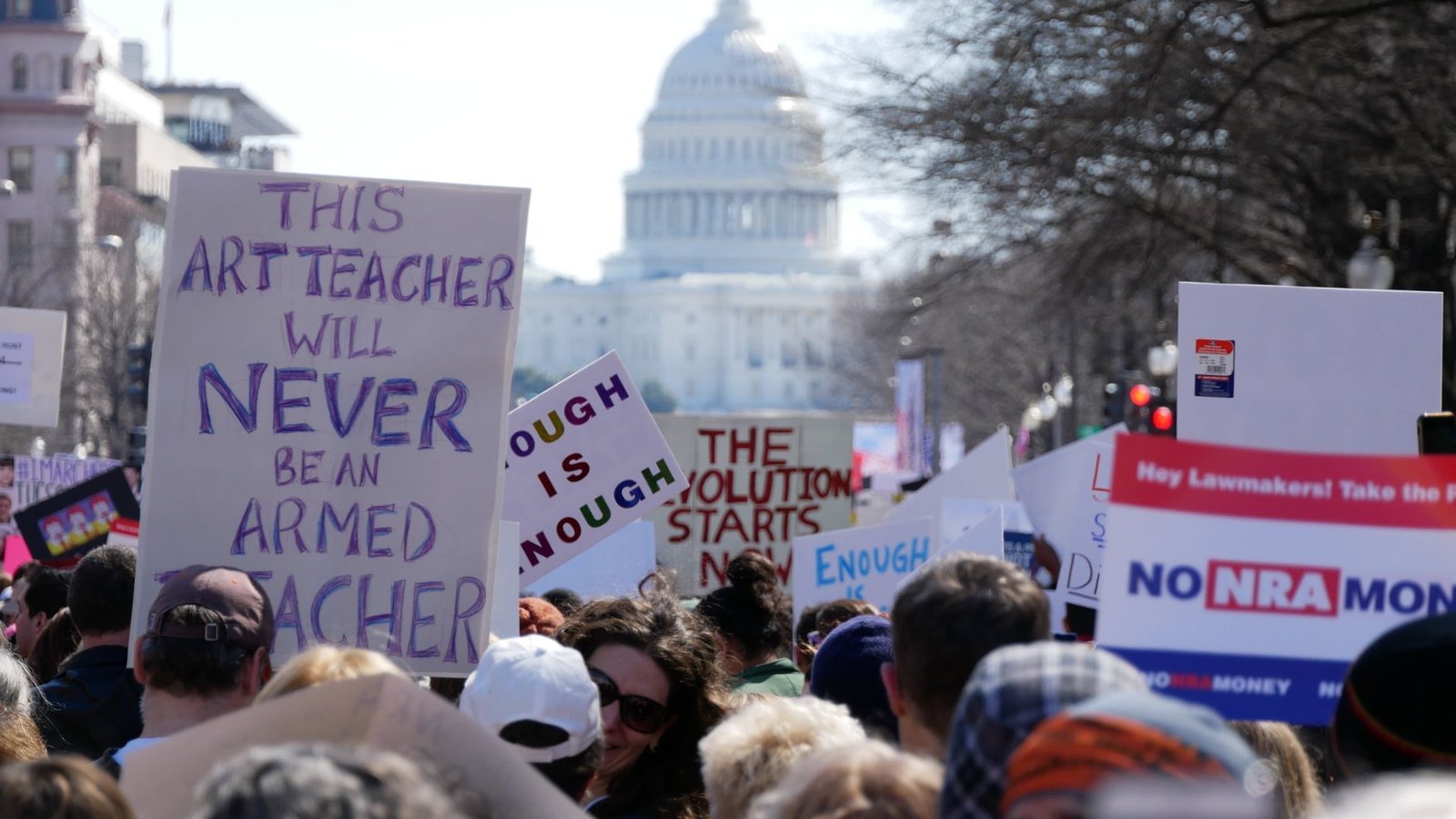 Protesters holding signs advocating for stricter gun control measures. — gun control debate