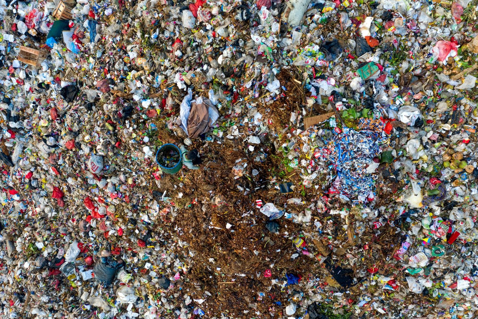 A photograph of overflowing landfills filled with discarded fast fashion clothing.