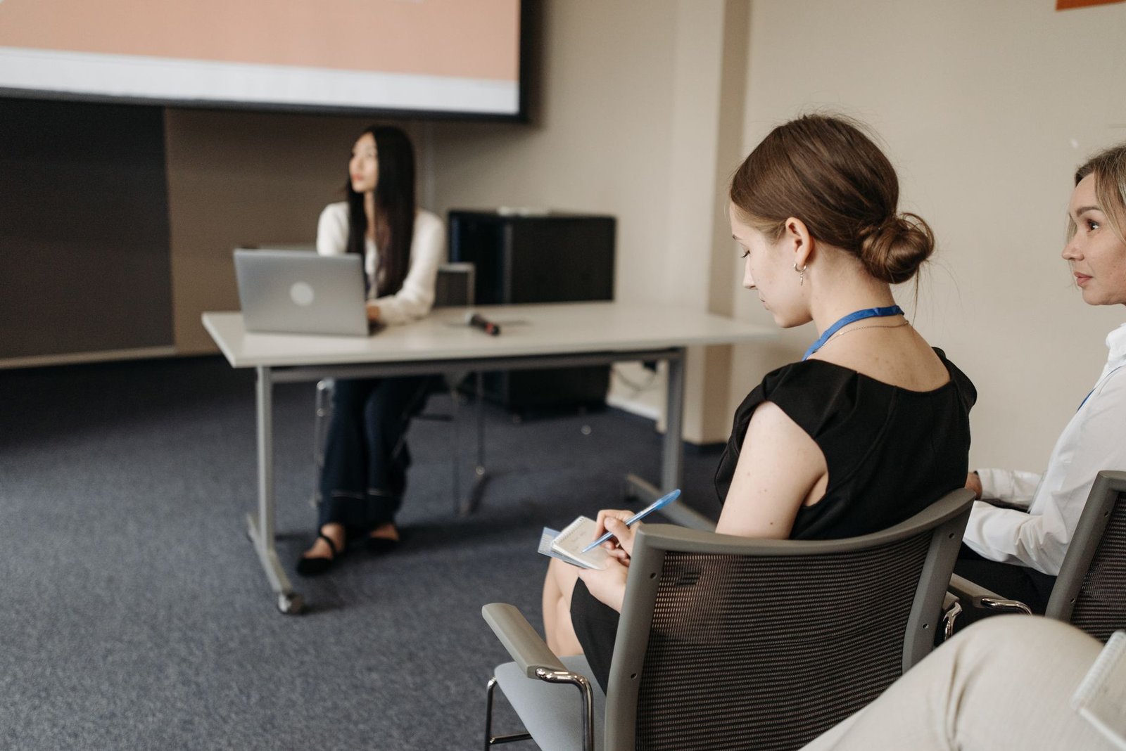 A close-up of a person taking notes while another speaker presents, highlighting active listening techniques. — listenin…