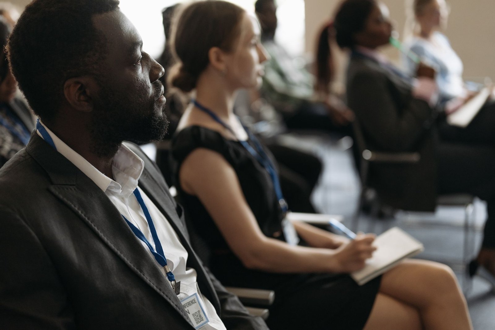 A close-up of a person taking notes while listening intently to another speaker during a debate. — listening skills in d…