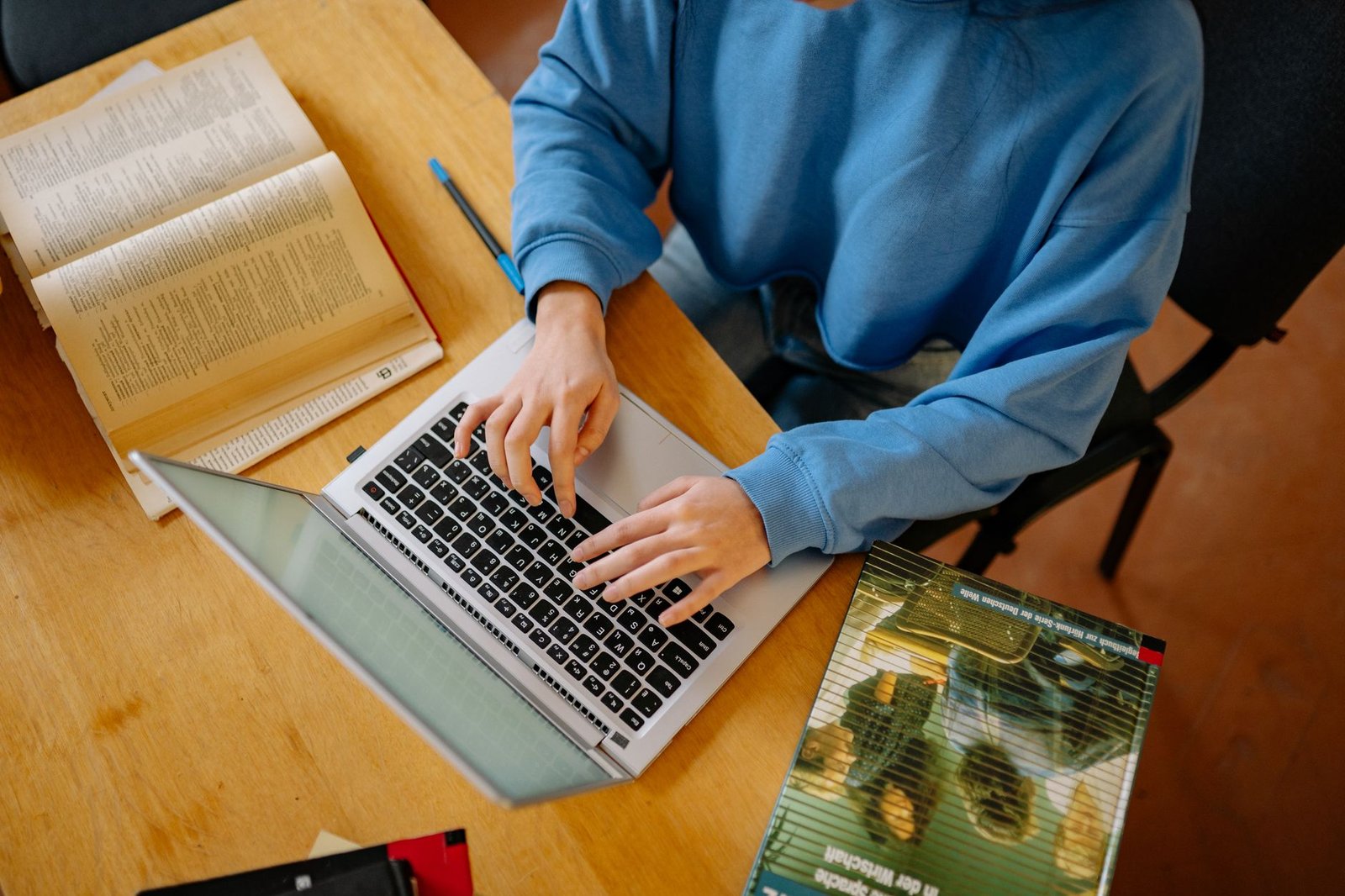 A person researching debate topics using books and a laptop. — public debate preparation
