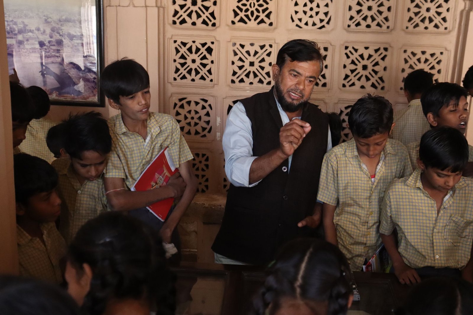 A teacher interacting with students during a financial education workshop, emphasizing practical money management skills. …