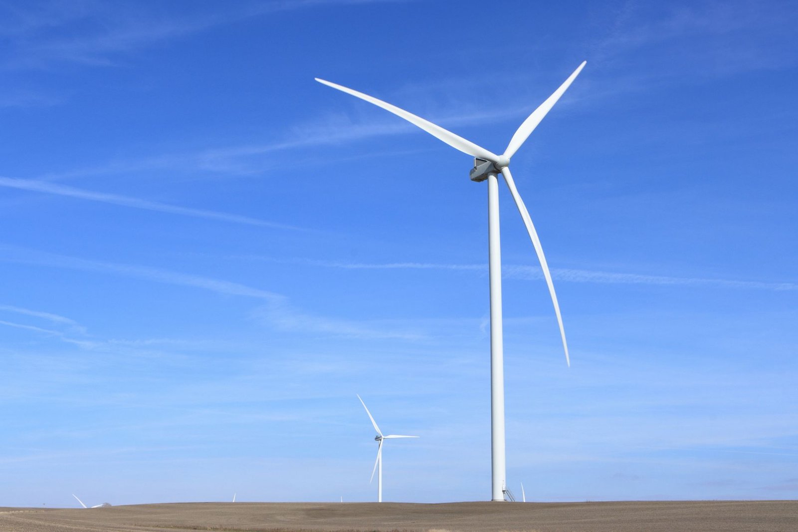 A wind farm with multiple turbines set against a clear blue sky. — renewable energy