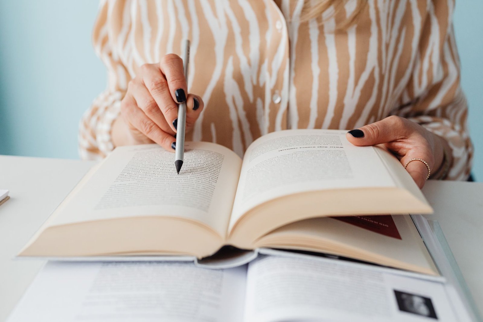 Image of a person researching debate topics with books and a laptop, highlighting the importance of thorough research in debate preparation.